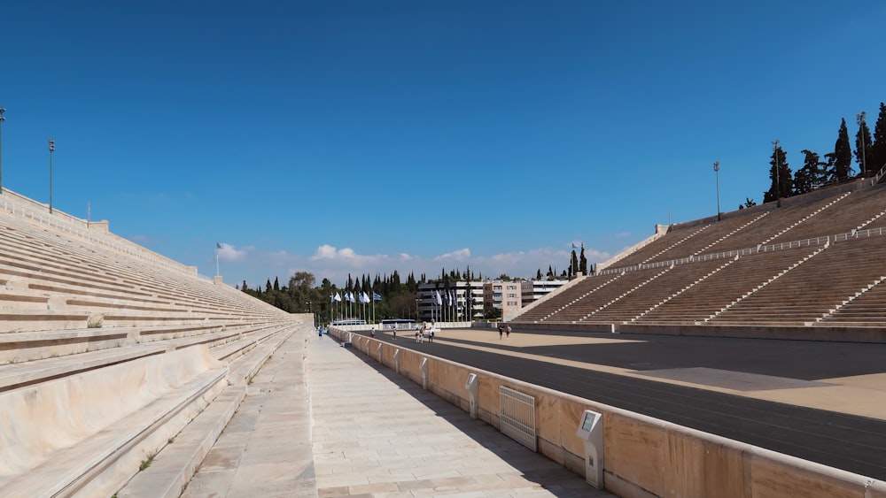 a road with a wall and a fence on the side with Panathenaic Stadium in the background