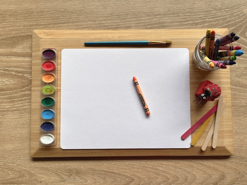 a white piece of paper with colorful markers and a few small round objects