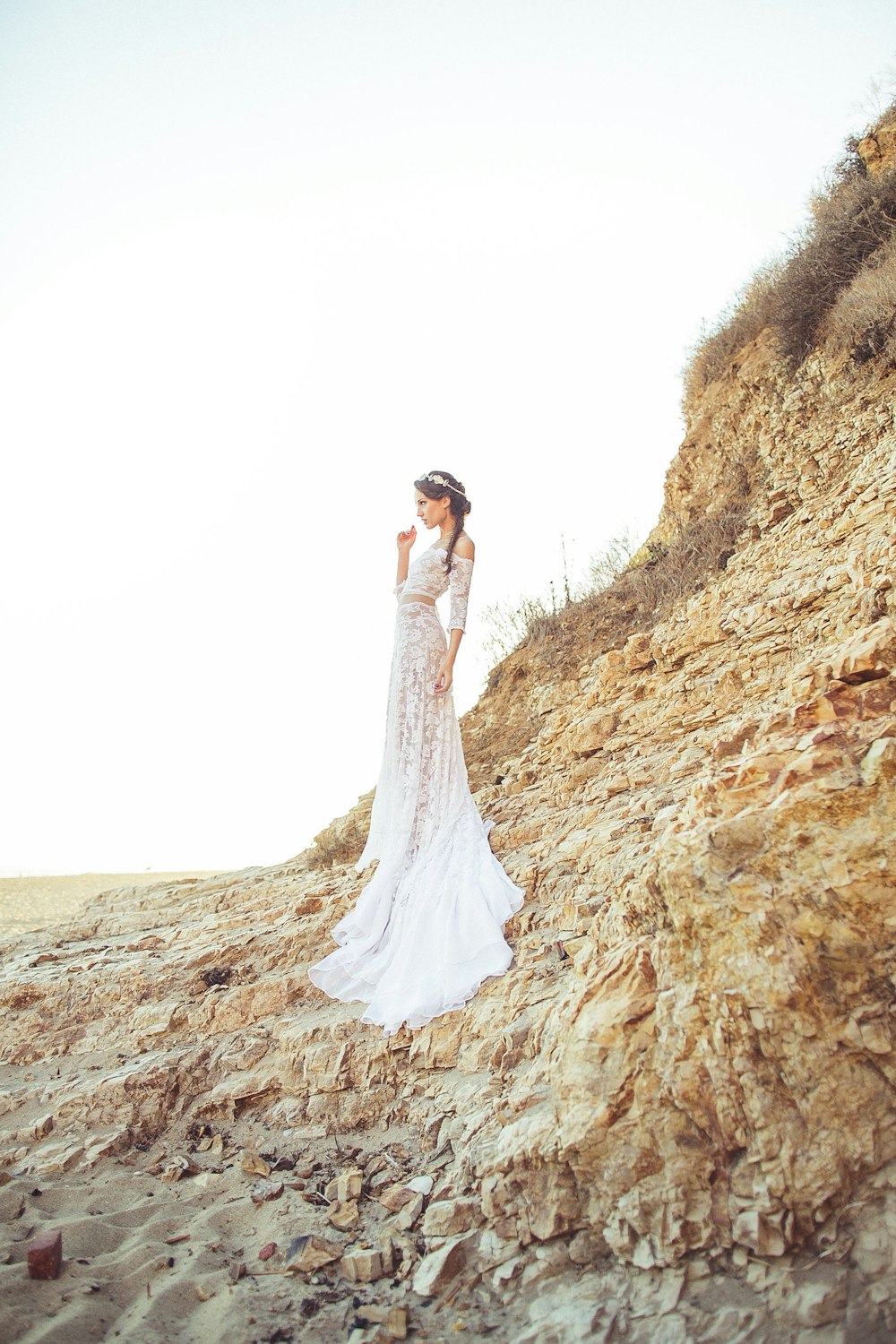 a person in a wedding dress standing on a rocky hill