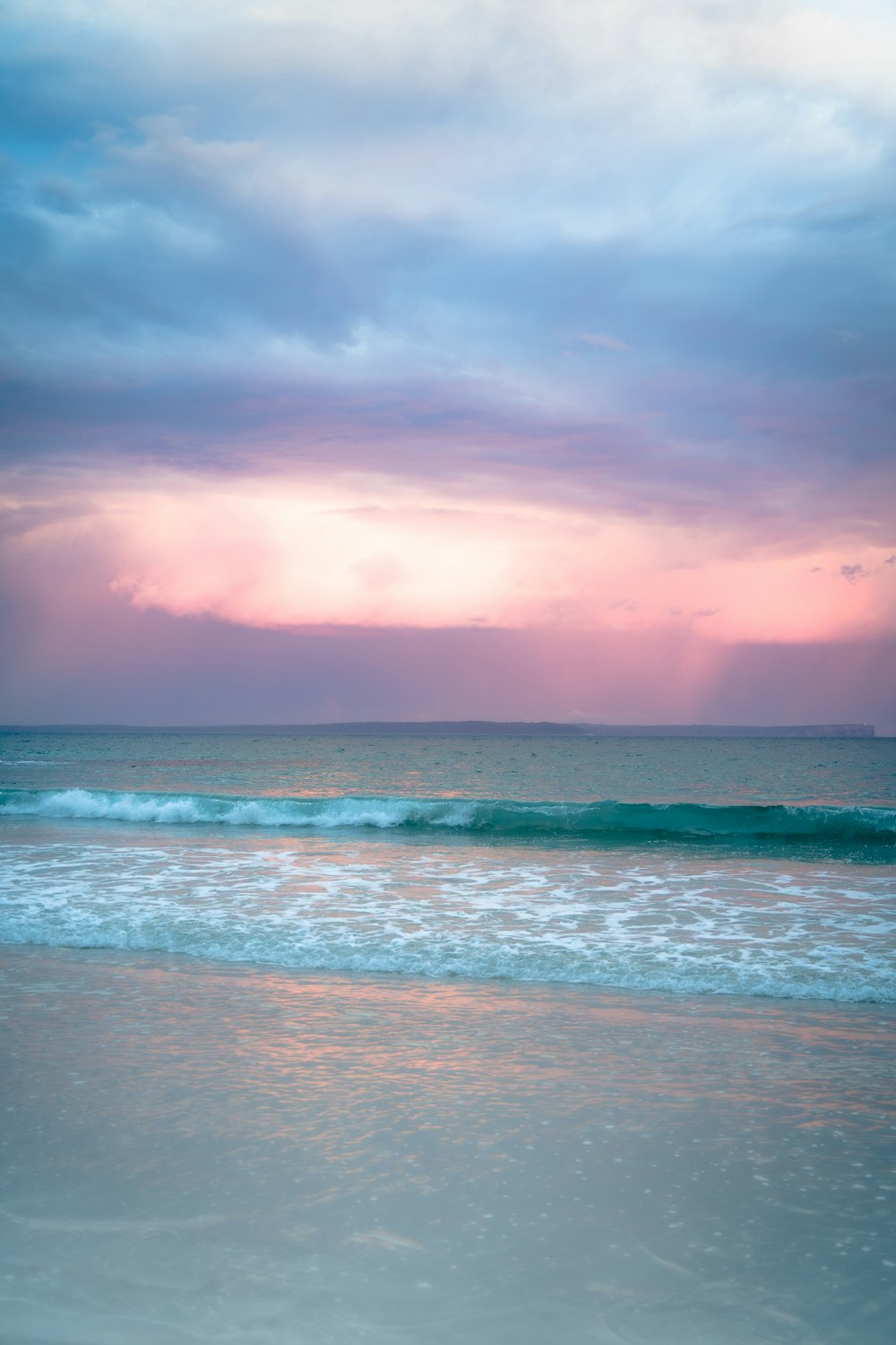 a beach with waves and a cloudy sky