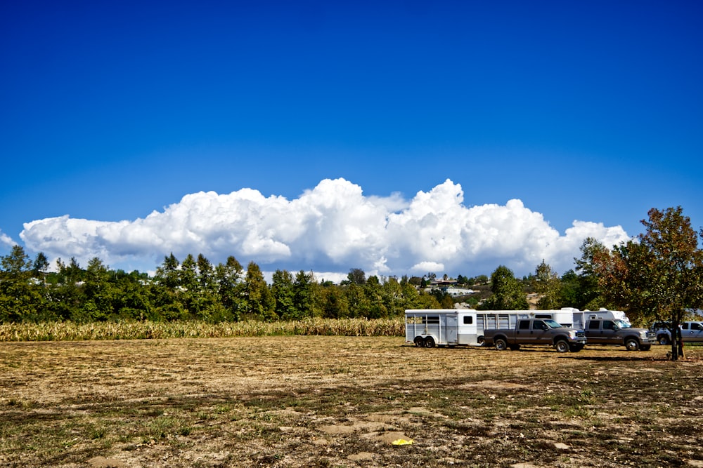 a group of trucks parked in a field with a cloud of smoke in the sky