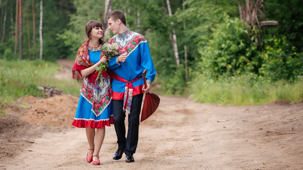 a man and woman walking down a dirt road