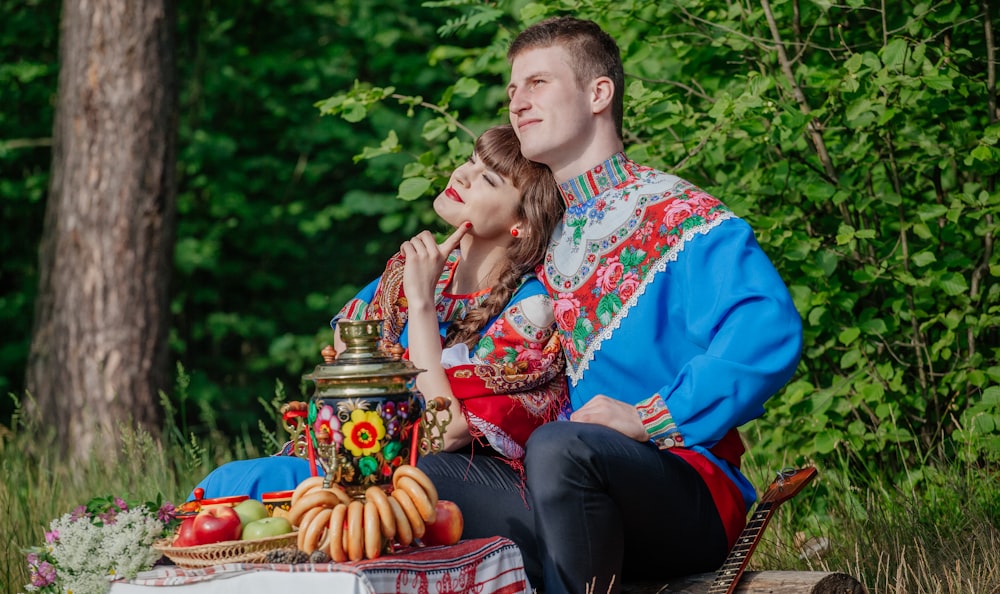 a man and woman sitting on a bench with a statue of a man