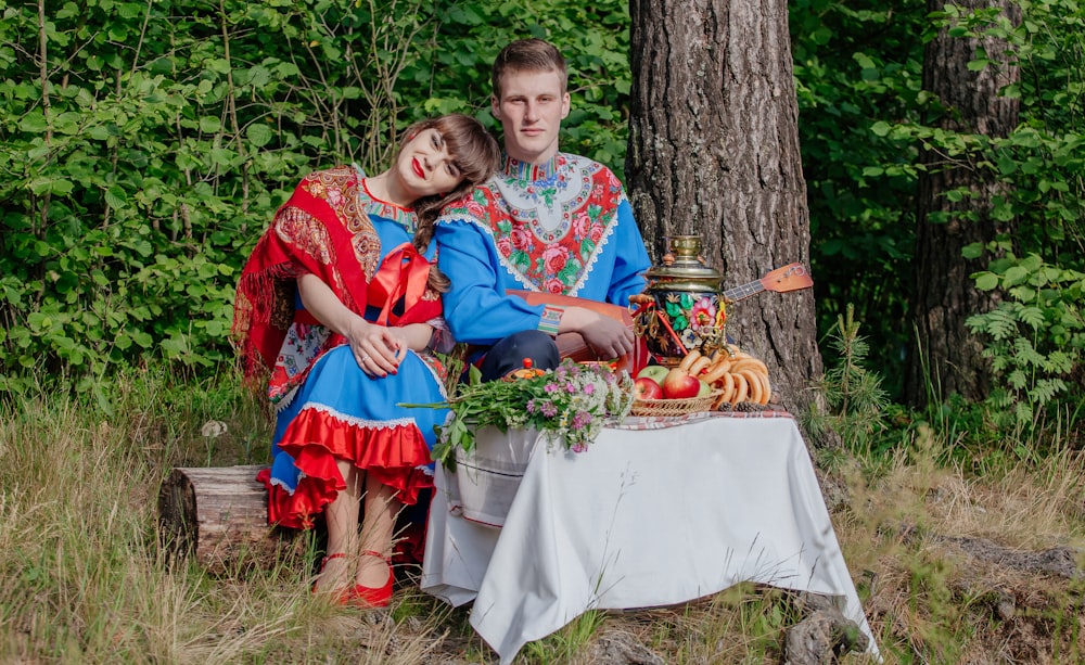 un uomo e una donna seduti su una panchina con un tavolo e frutta