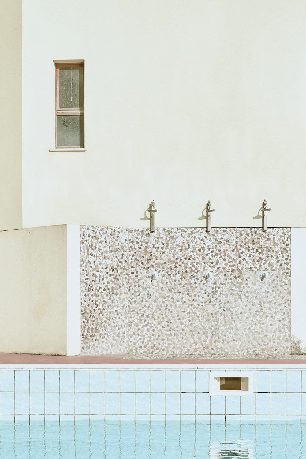 a pool with a stone wall and a cross on top