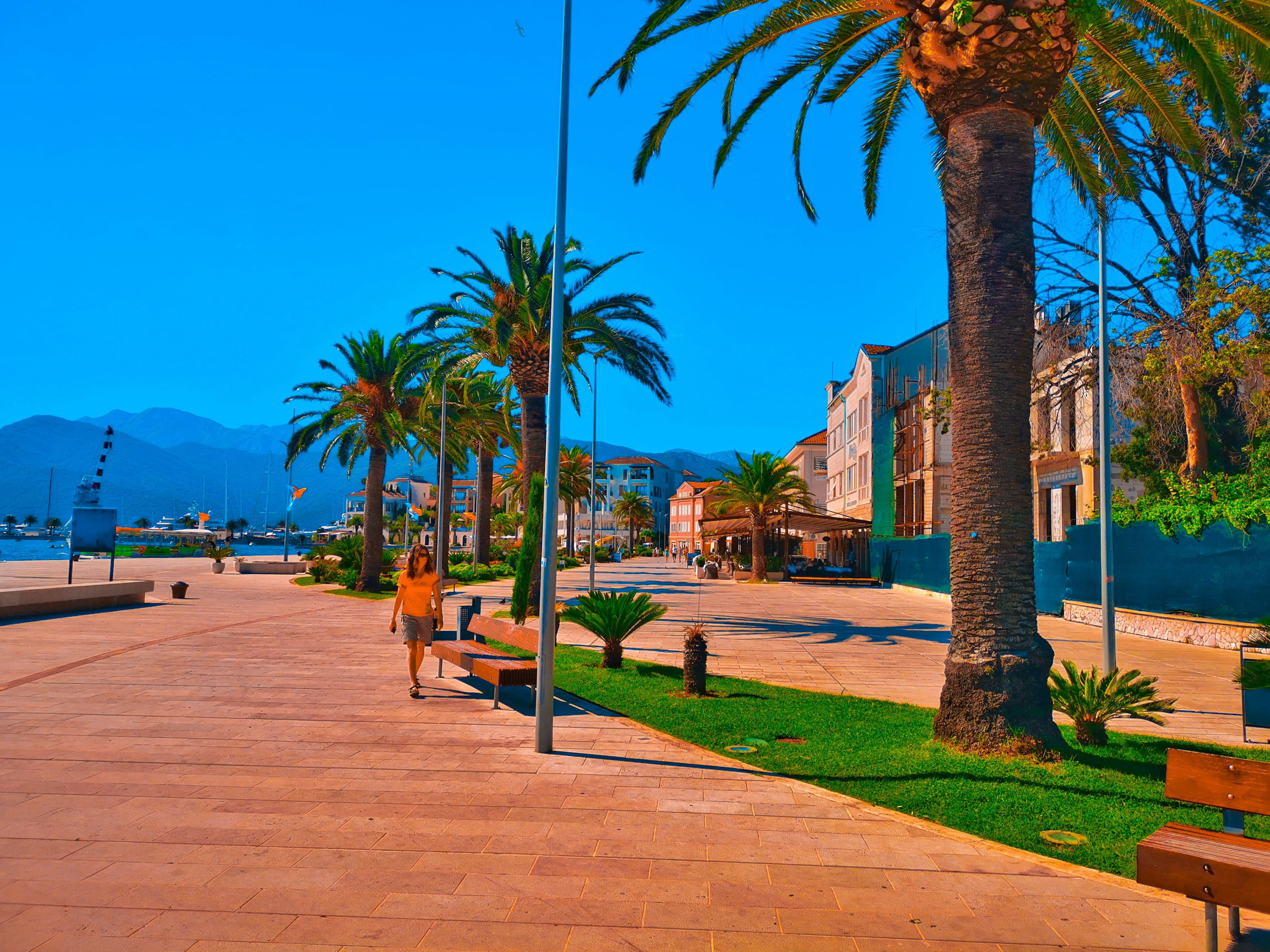 A smiling woman enjoying a sunny walk along Marbella's beach promenade.