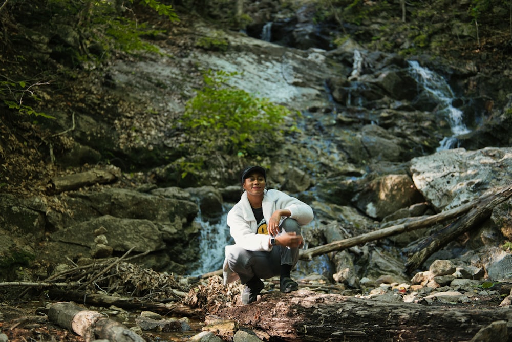 a man sitting on a rock by a waterfall