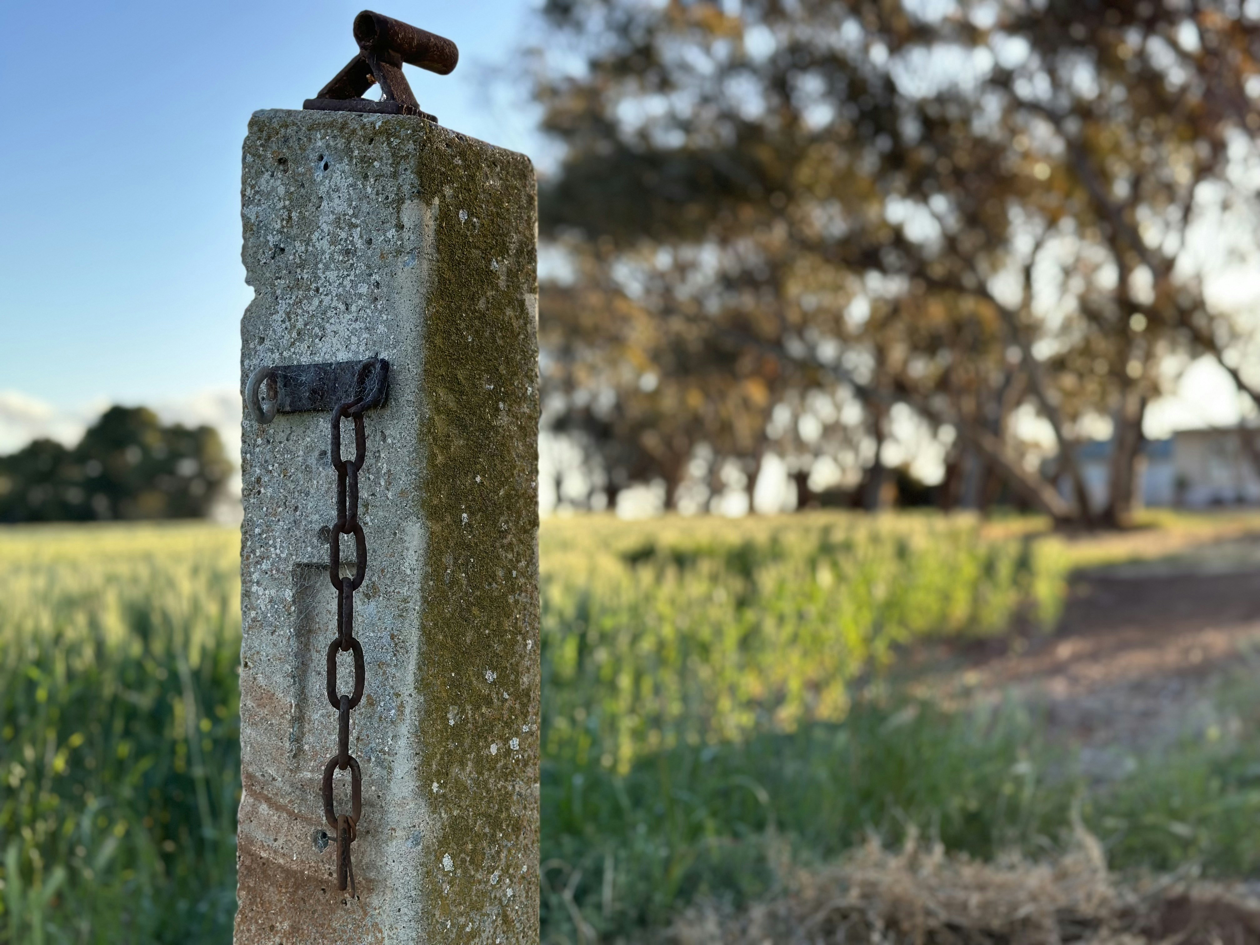 A photo of a post with a farm in the background.