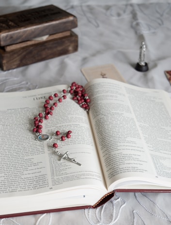 A collection of prayer books and rosaries resting on a wooden shelf, worn with loving use.