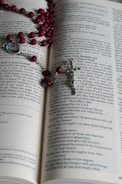 Hands holding a rosary over an open Bible