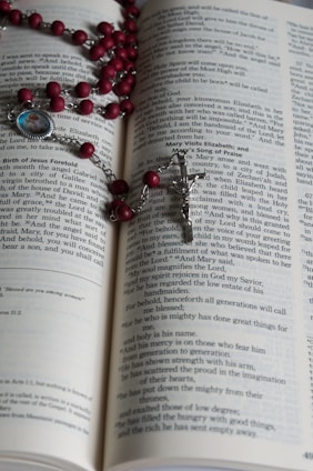 A warm, inviting image of an open Bible with a rosary resting on its pages, softly lit by candlelight.