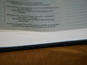 A close-up view of an open book lying on a wooden surface, with readable text on the visible page that includes a philosophical or motivational quote.