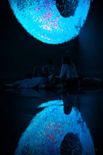 A serene group session in a dimly lit room with deep purple and neon accents, participants immersed in a respiroflow experience.