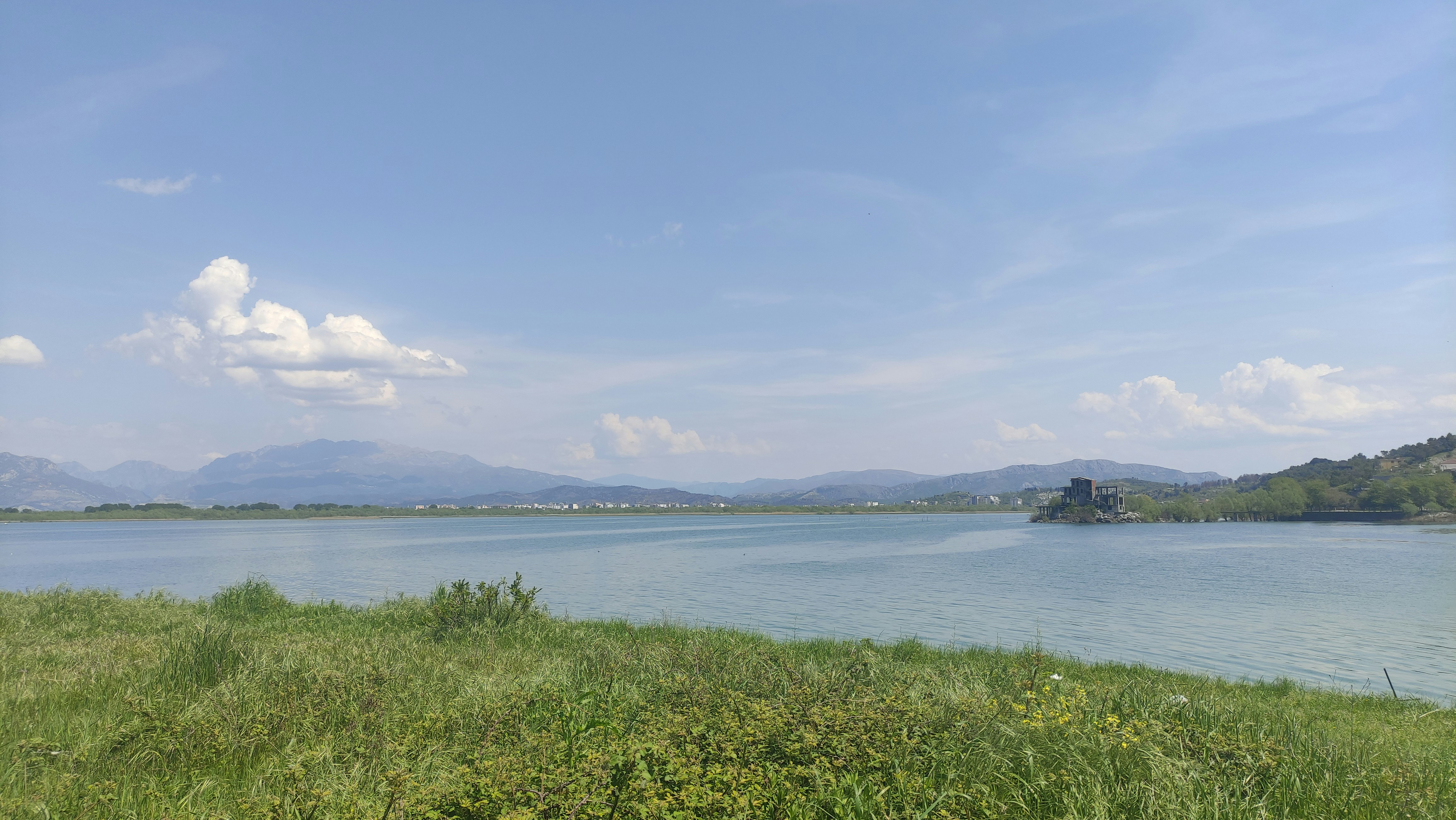 a body of water with grass and hills around it