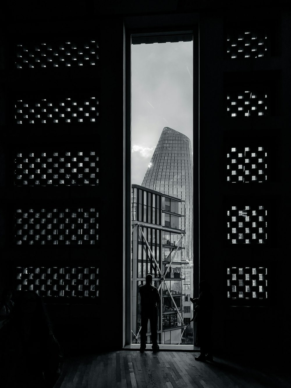 a person standing in a hallway between tall buildings