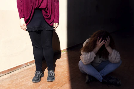 a woman sitting on the floor next to a man standing on a wall