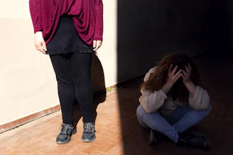 a woman sitting on the floor next to a man standing on a wall