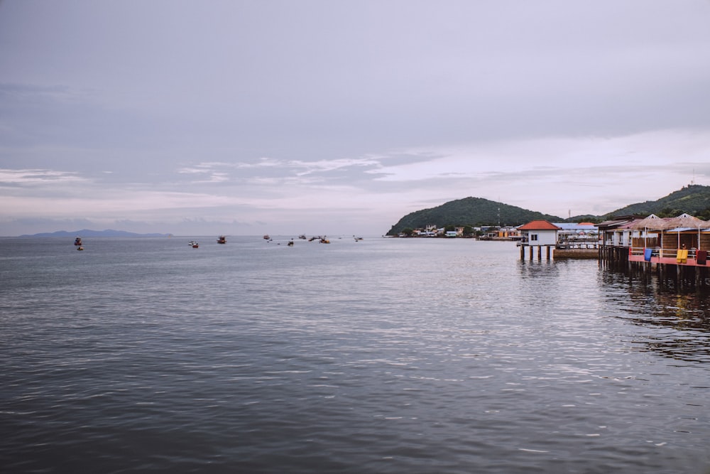 a body of water with buildings and hills in the background