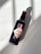 A bottle of non-alcoholic rum and cola with a zero-proof label is placed on a light surface, casting a shadow. The design is minimalistic with a prominent red and white label.