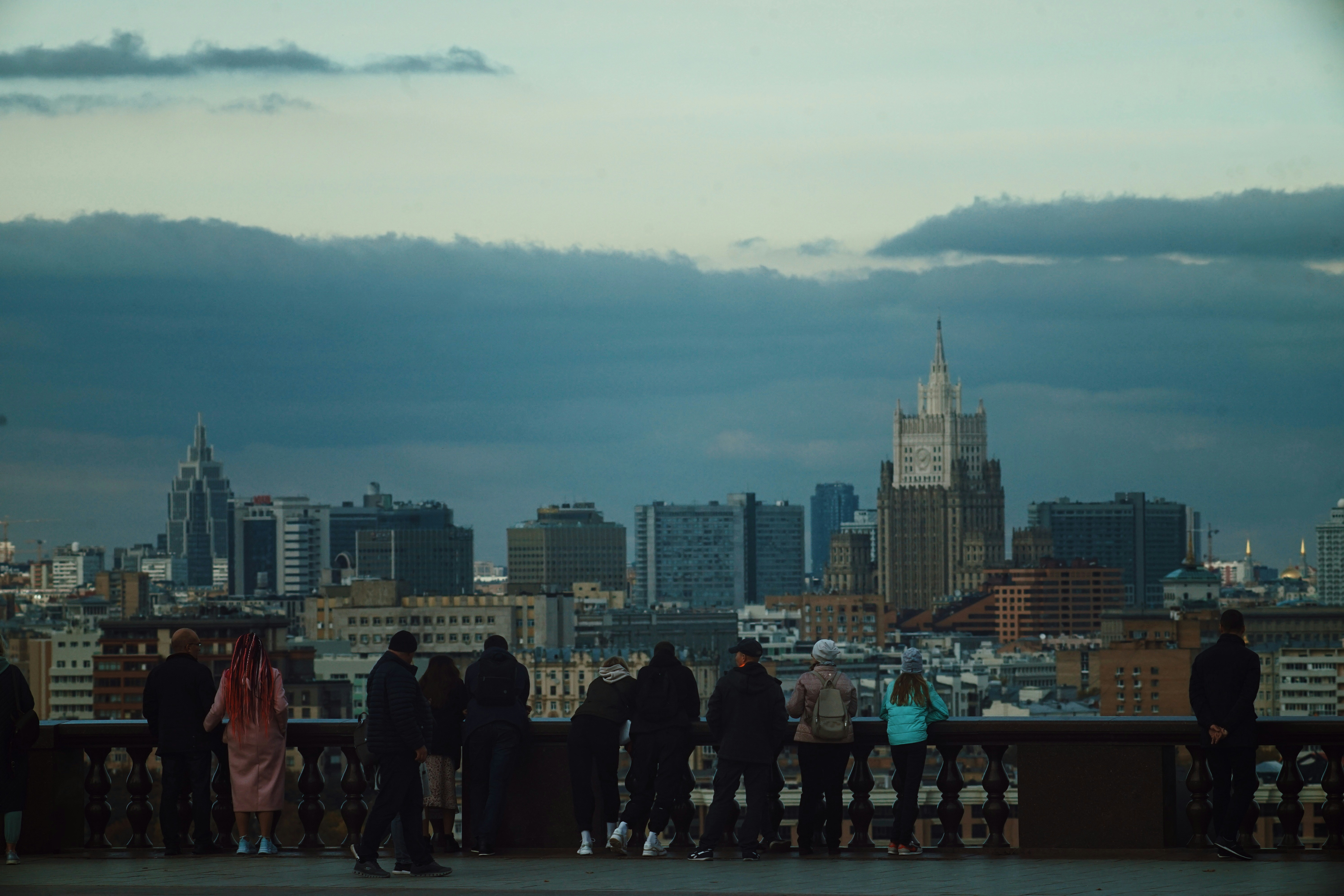 A group of people standing on a rooftop overlooking a city photo – Free ...