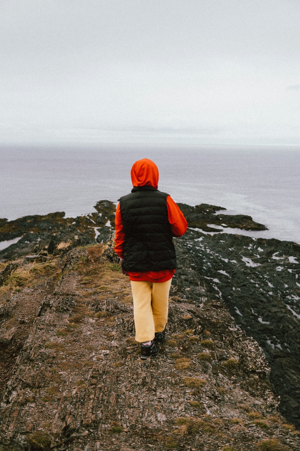 a person standing on a rocky hill overlooking the ocean