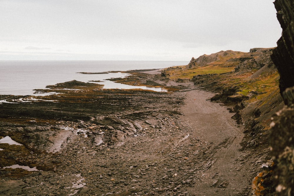 a rocky beach with a body of water in the background