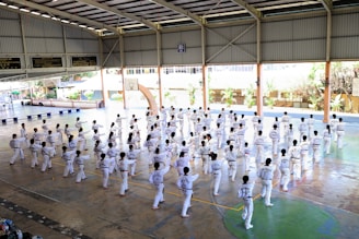 a group of people in white karate uniforms in a room with trees