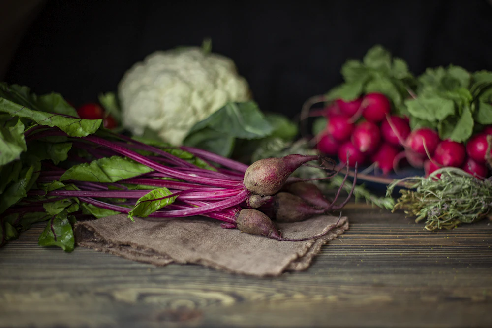 Fresh vegetables including beetroot and cauliflower arranged on a rustic wooden table