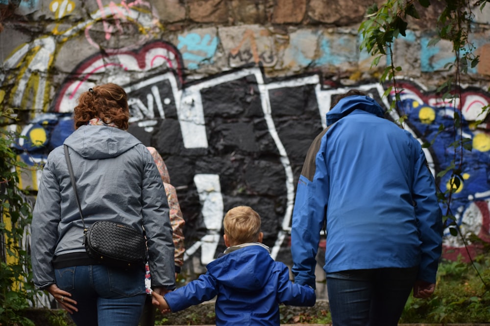 a group of people walking by a wall with graffiti