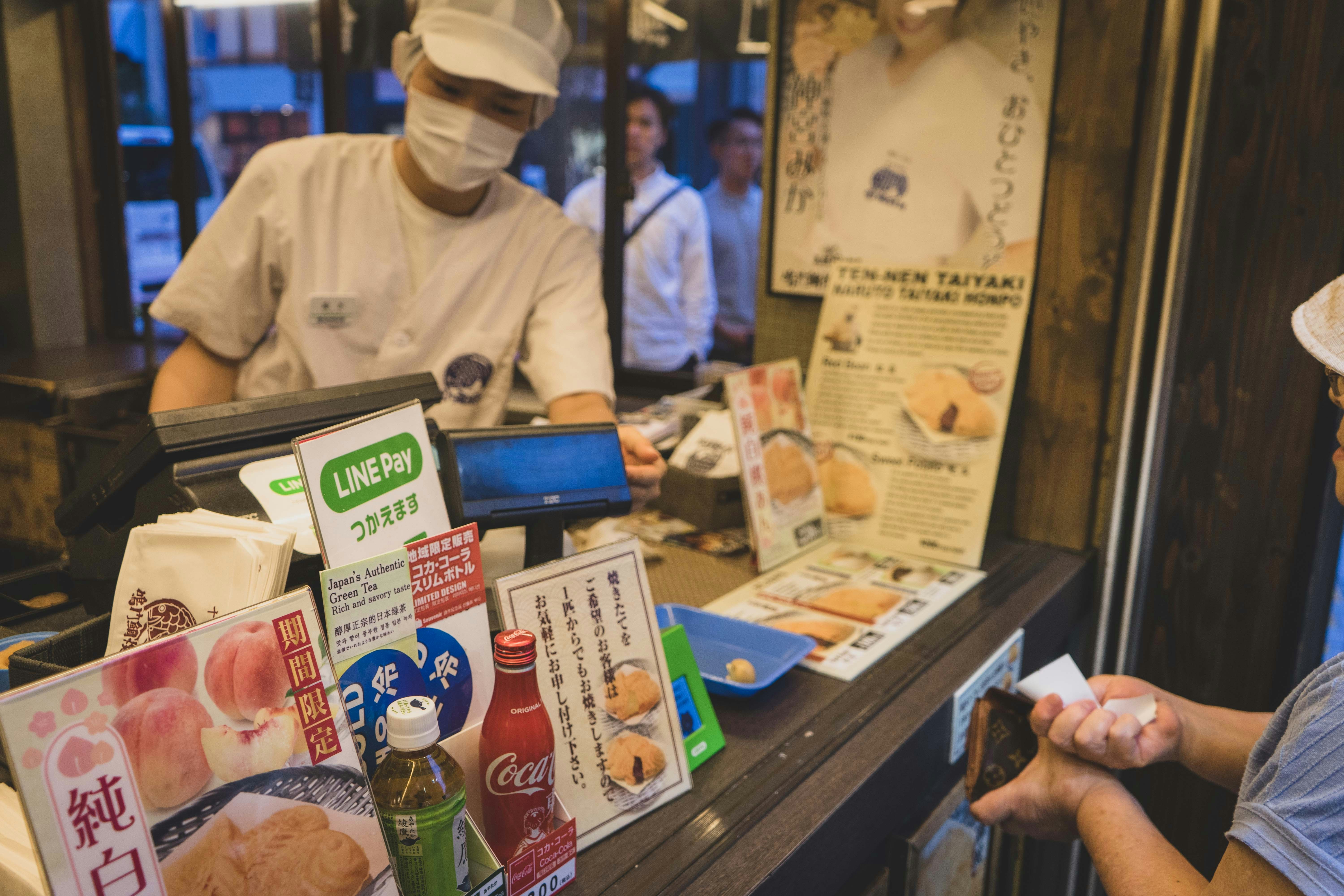Convenience store cashier pouring oden broth into a cup