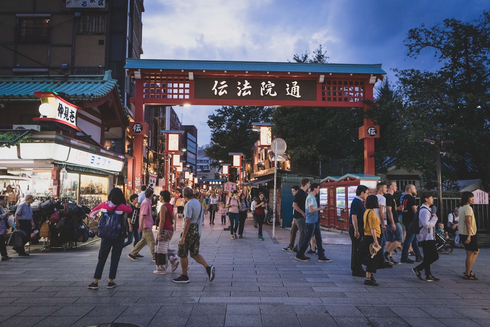 a crowd of people walking in front of a sign