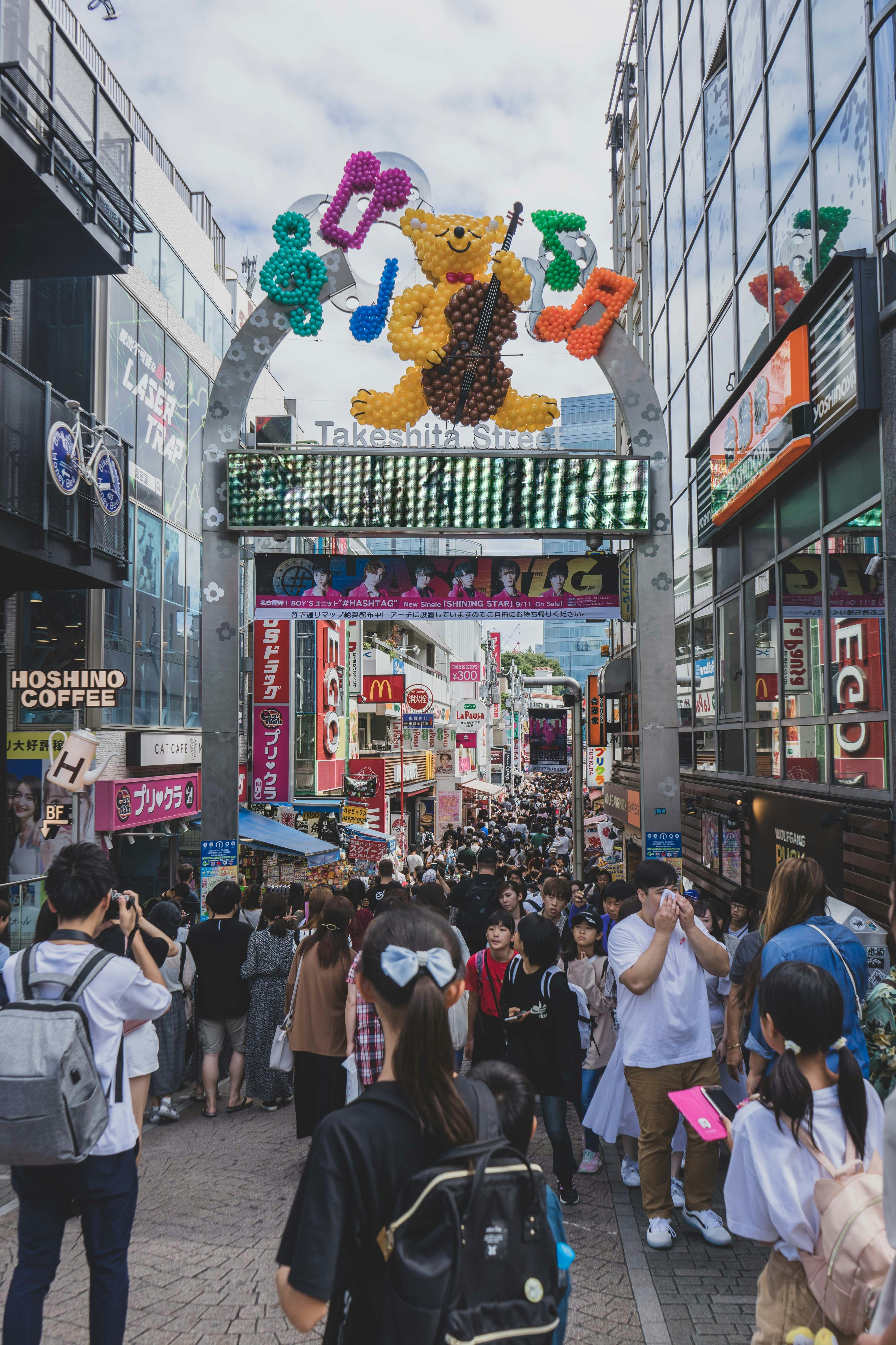 Una multitud de personas caminando por una calle con un gran cartel