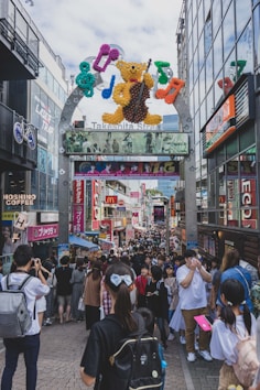 a crowd of people walking on a street with a large sign
