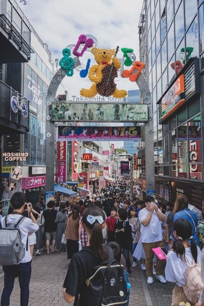 a crowd of people walking on a street with a large sign