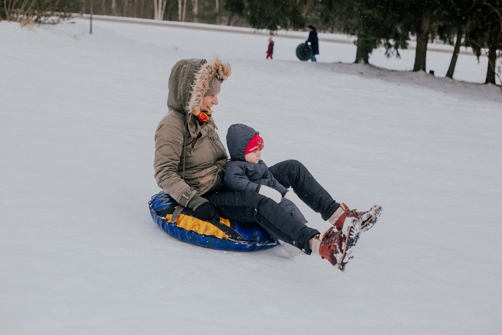 a person and a child sitting in the snow