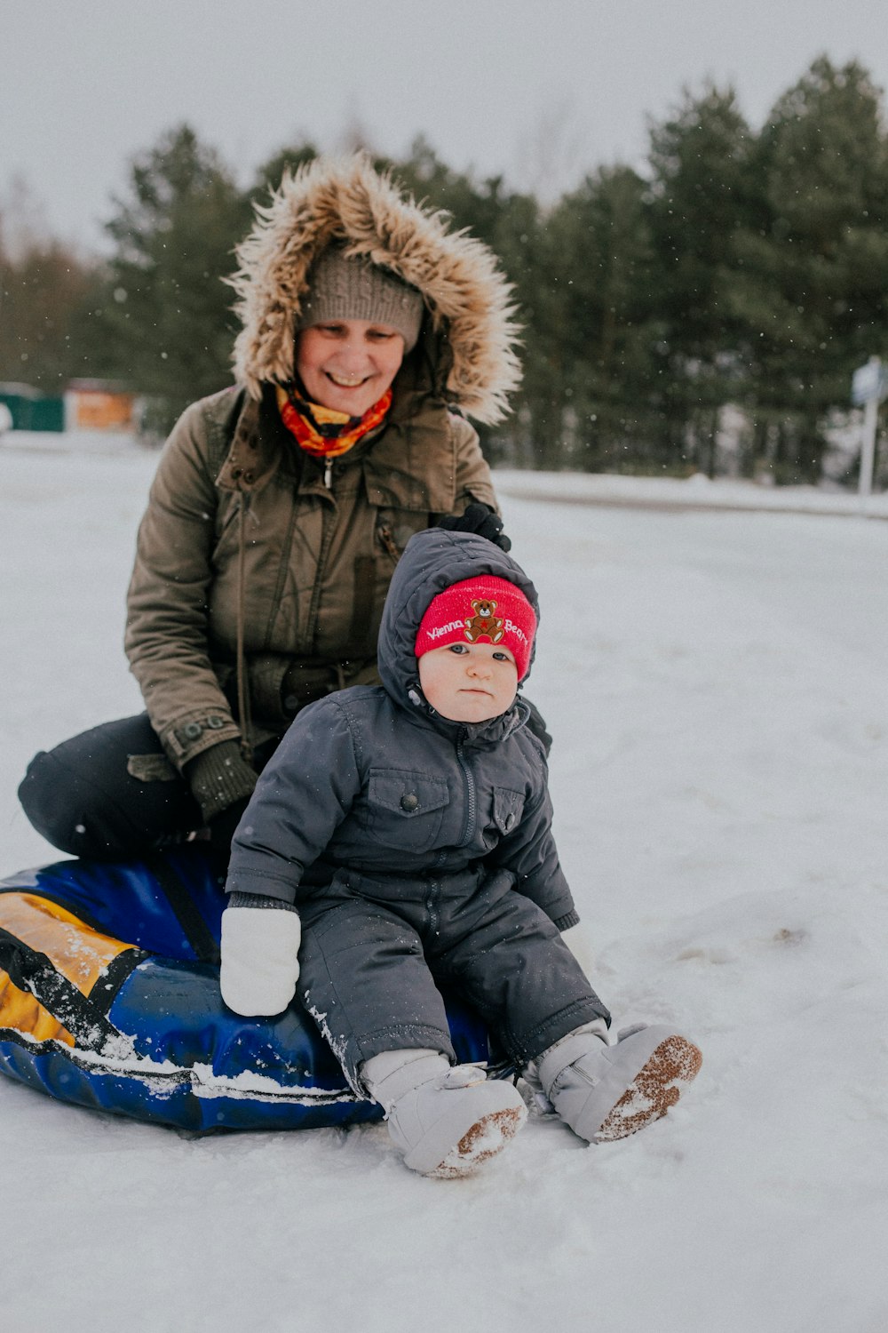 a woman and a child on a sled in the snow