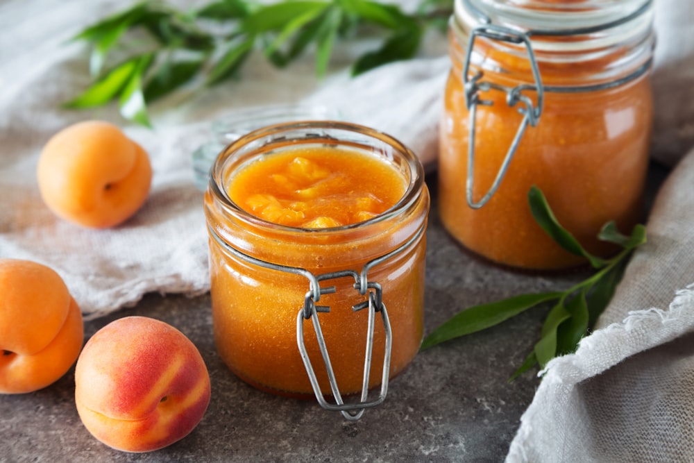 a jar of orange juice next to a jar of oranges