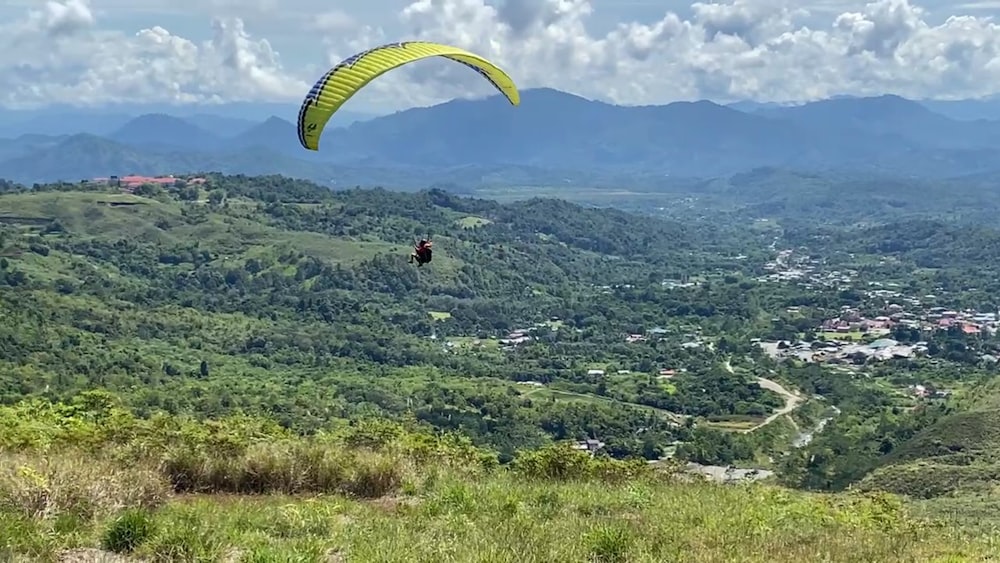 a person parachuting over a valley