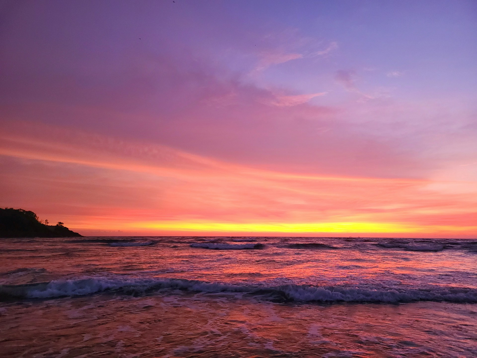 a beach with waves and a sunset