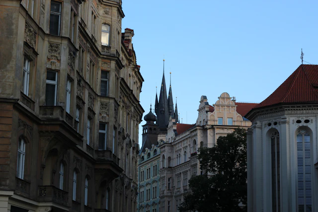 Ornate Art Nouveau facades along a Josefov street at dusk, with the Church of Our Lady before Tyn's spires visible behind.
