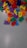 Colorful plastic alphabet letters scattered across a light gray surface. The letters are vibrant, including red, blue, yellow, green, orange, and purple shades. They appear to be jumbled and are likely used for educational or playful purposes.