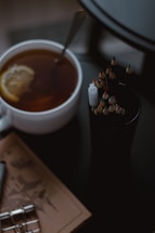 A warm cup of lulutox tea beside a notebook and pen on a wooden table.