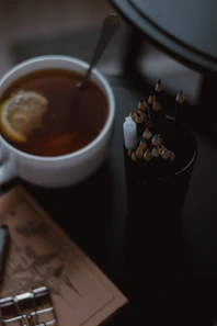 A warm cup of steaming herbal tea beside an open journal with a pen.