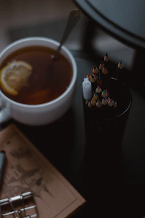 A warm cup of steaming herbal tea beside an open journal with a pen.