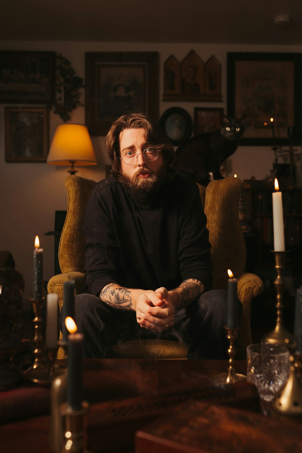 a man with a beard sitting in a chair with a group of candles