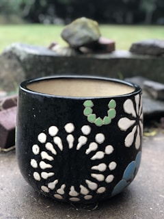 Close-up of a rugged, sturdy ceramic pot with a matte finish, sitting outdoors with fresh green foliage.