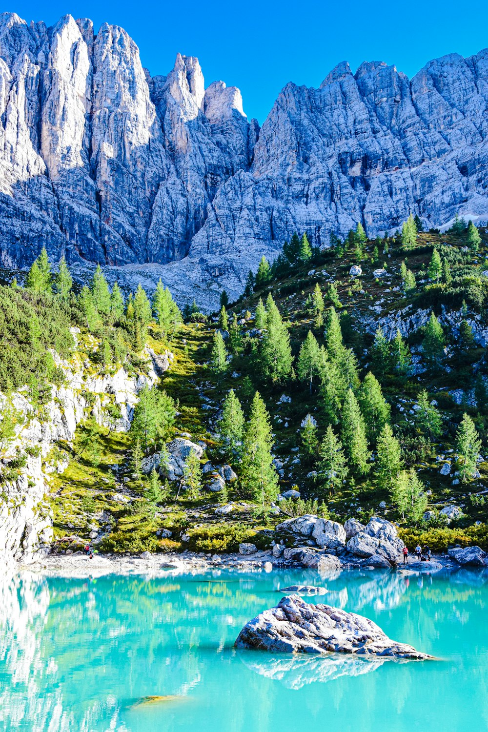 a rocky mountain with trees and water below