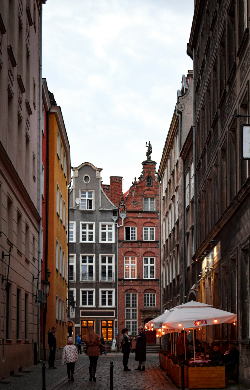 people walking on a street between buildings