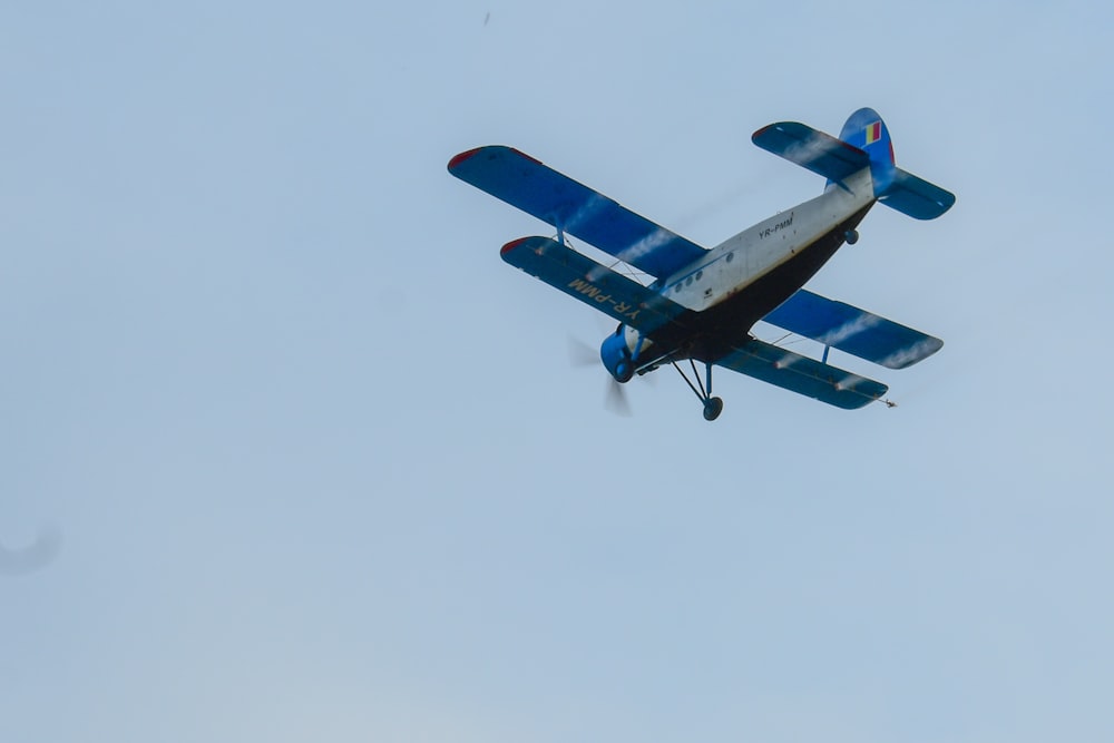 a blue and white airplane flying in the sky