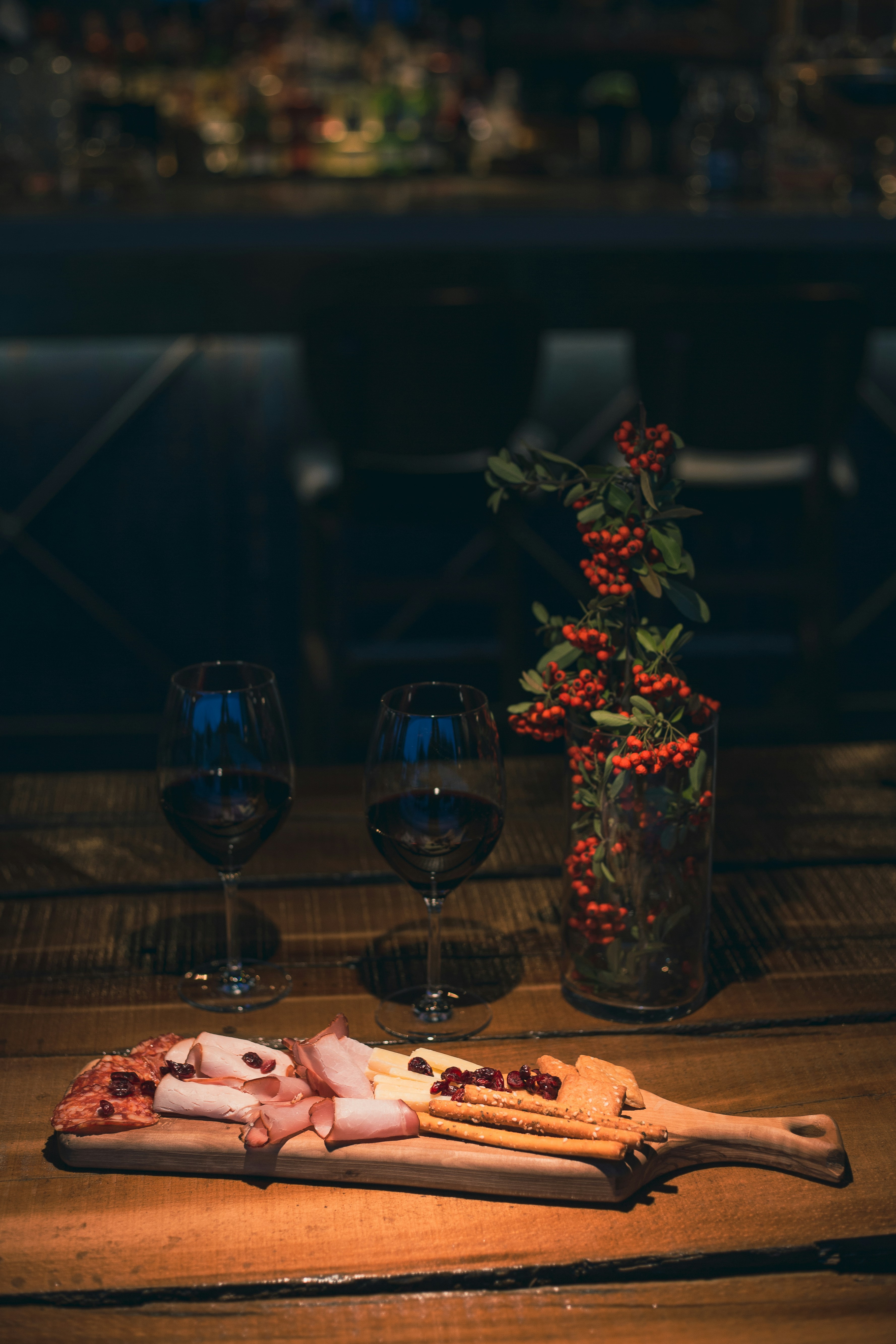 Copas de vino y tabla de embutidos sobre una mesa rústica.